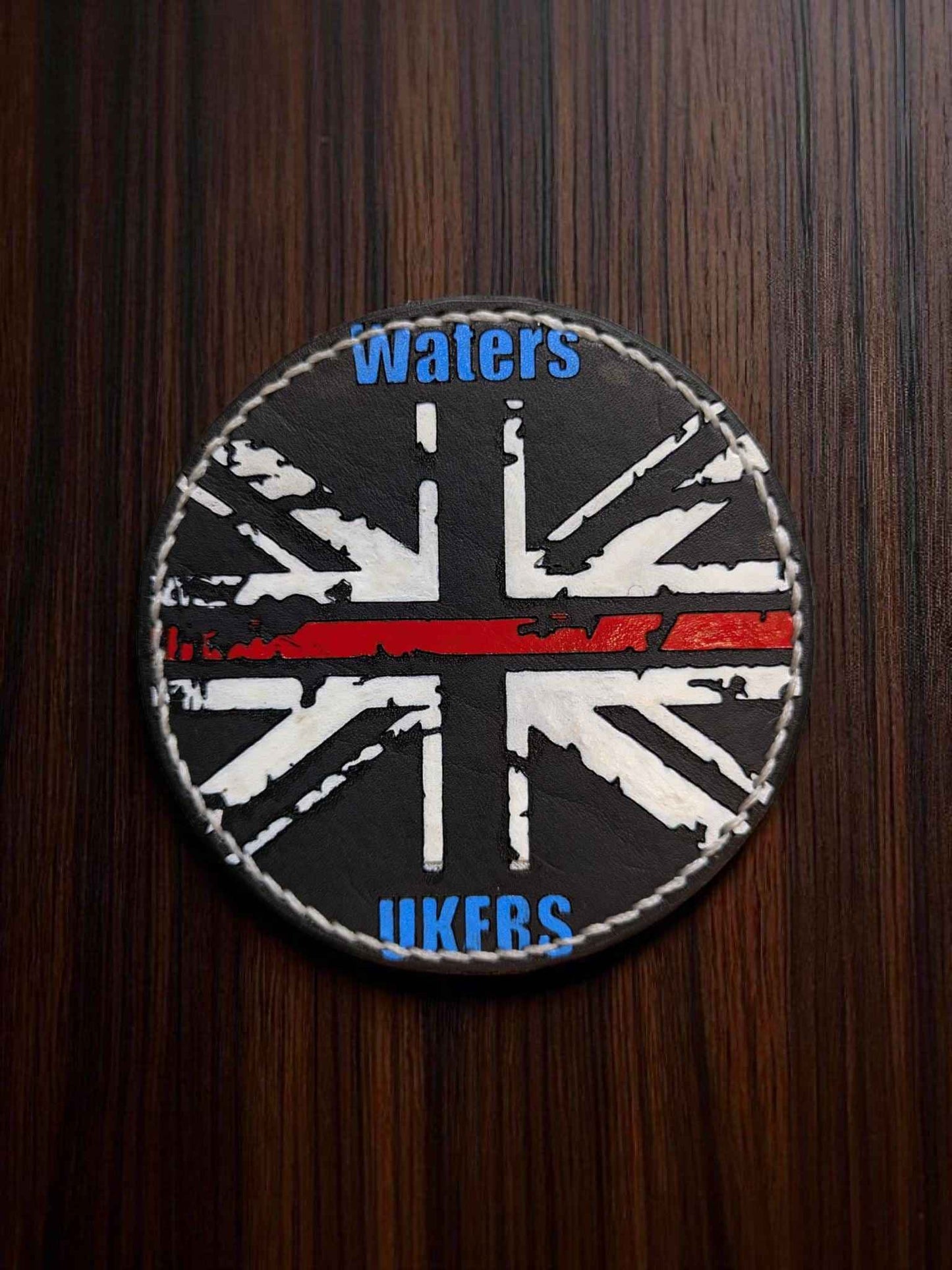 A closed up image of a Bespoke Fire Service Velcro Shoulder Badges displaying the union jack on a dark tabletop.