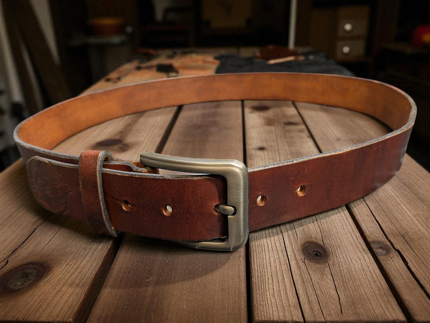A Brown Leather Belt displayed on a rustic workbench.
