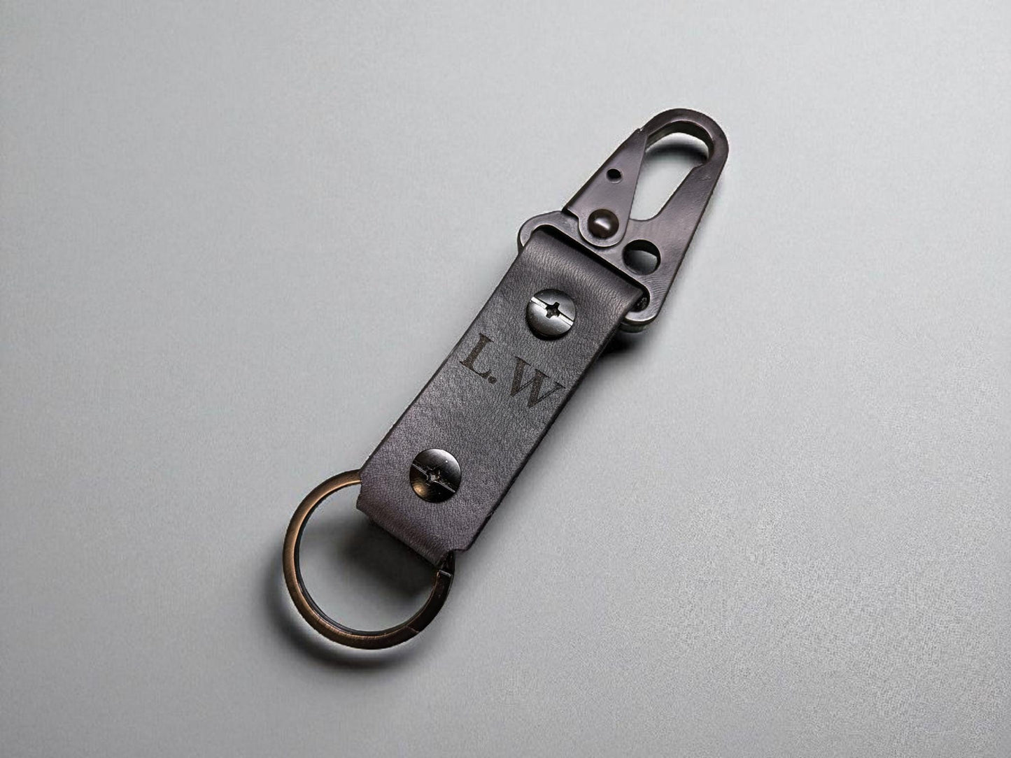 Black leather keychain with metal clip on a gray background