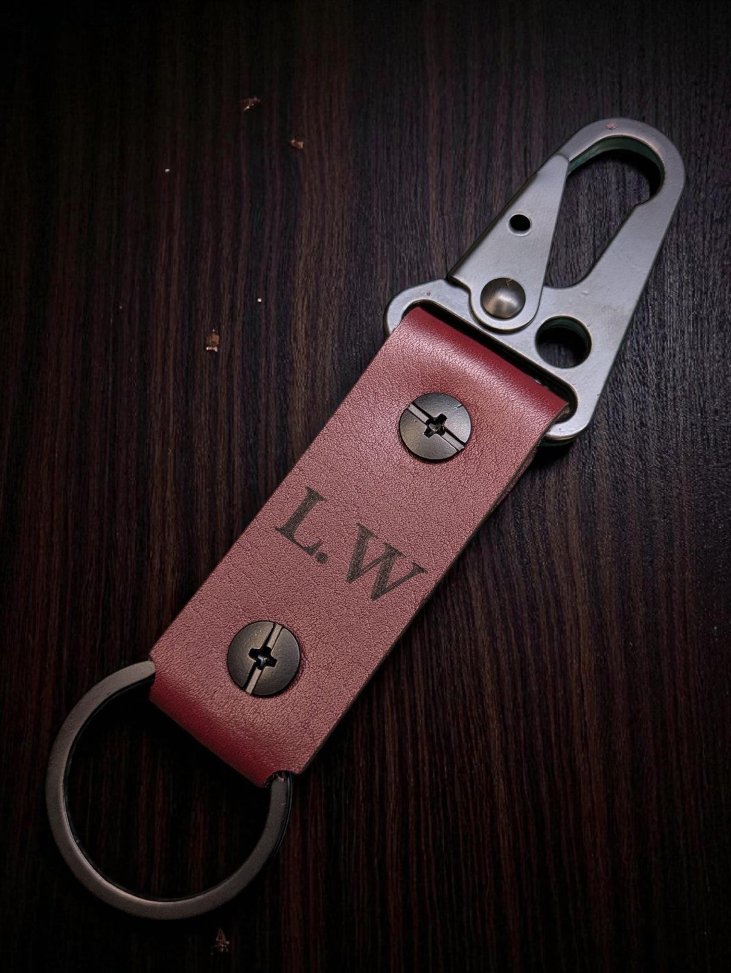 Red leather keychain with metal clip on a dark wooden surface