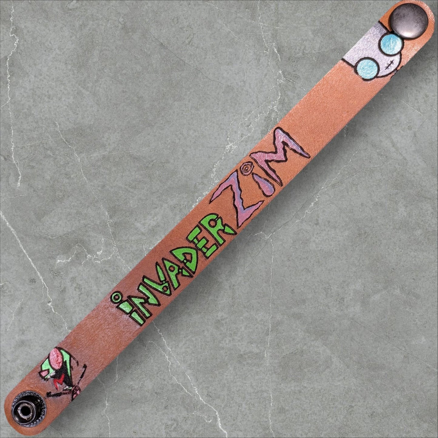 Leather wristband with 'Invader Zim' design on a gray marble background
