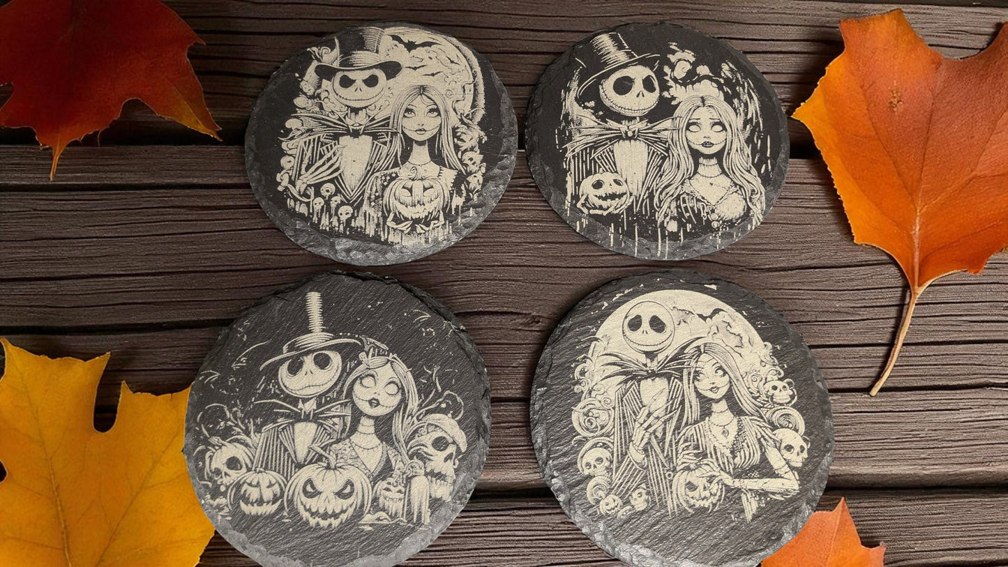 Four round slate coasters with Halloween-themed designs on a wooden surface with autumn leaves.