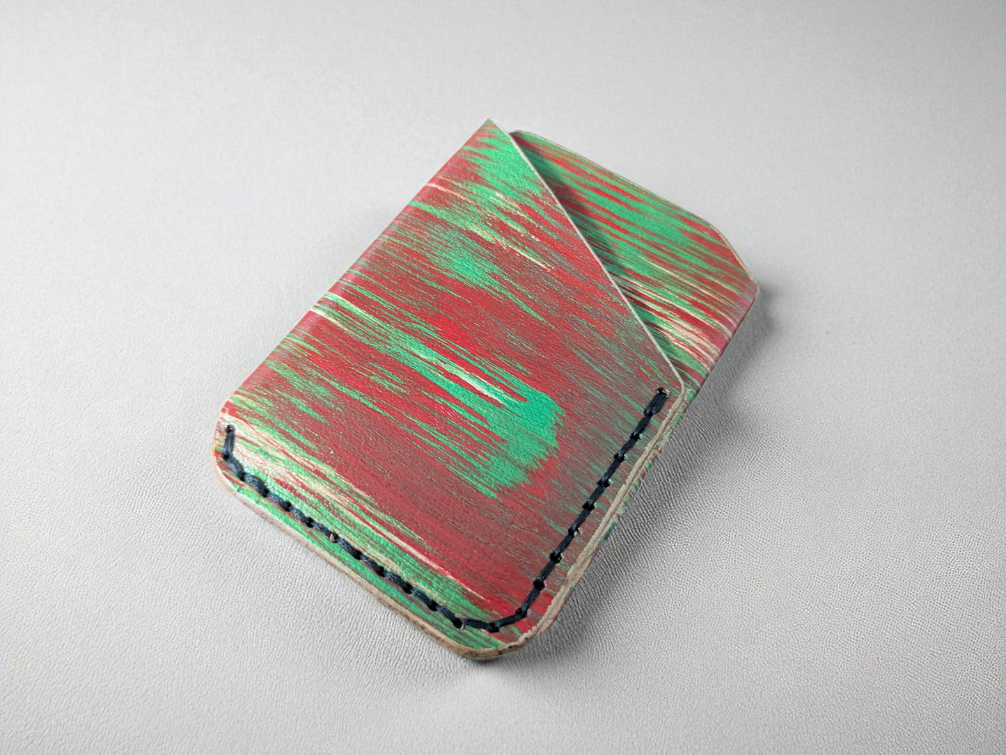 Red and green wallet with black stitching on a light gray background