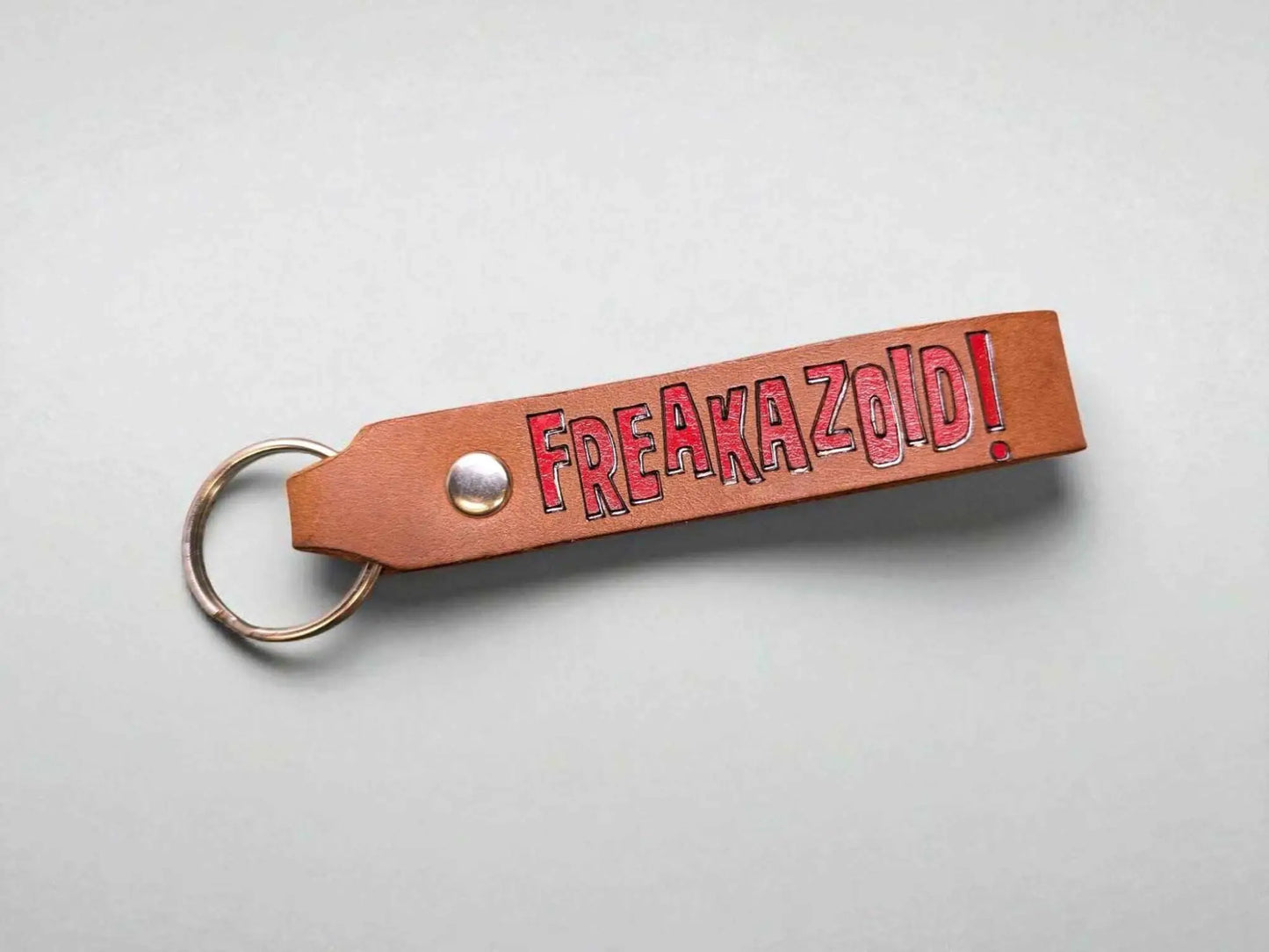 A Freakazoid themed Handmade Leather Keychain displayed on a white countertop.