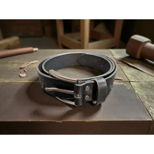 Black leather belt with silver buckle on a wooden surface