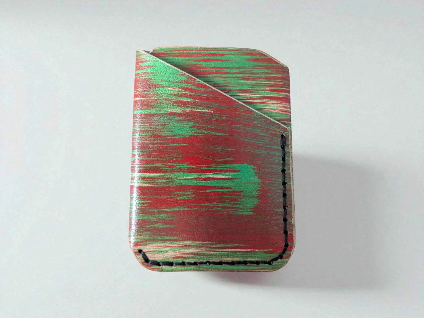 Red and green splash-dyed vegetable tanned leather card wallet, side angle showing stitched edge