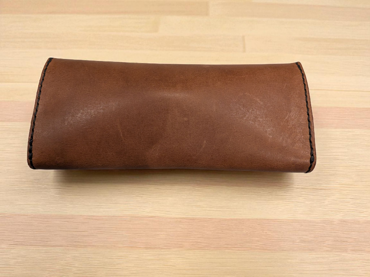 Brown leather Sunglasses Case on a wooden table.