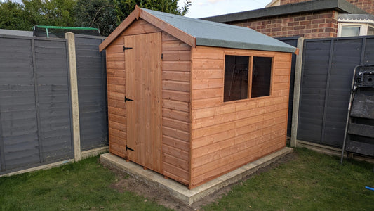 New shed standing proud in the corner of a garden.