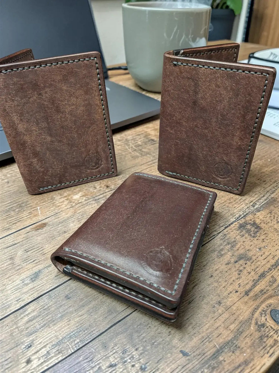 Brown Venturi Card Holder Wallets standing upright on a wooden desk