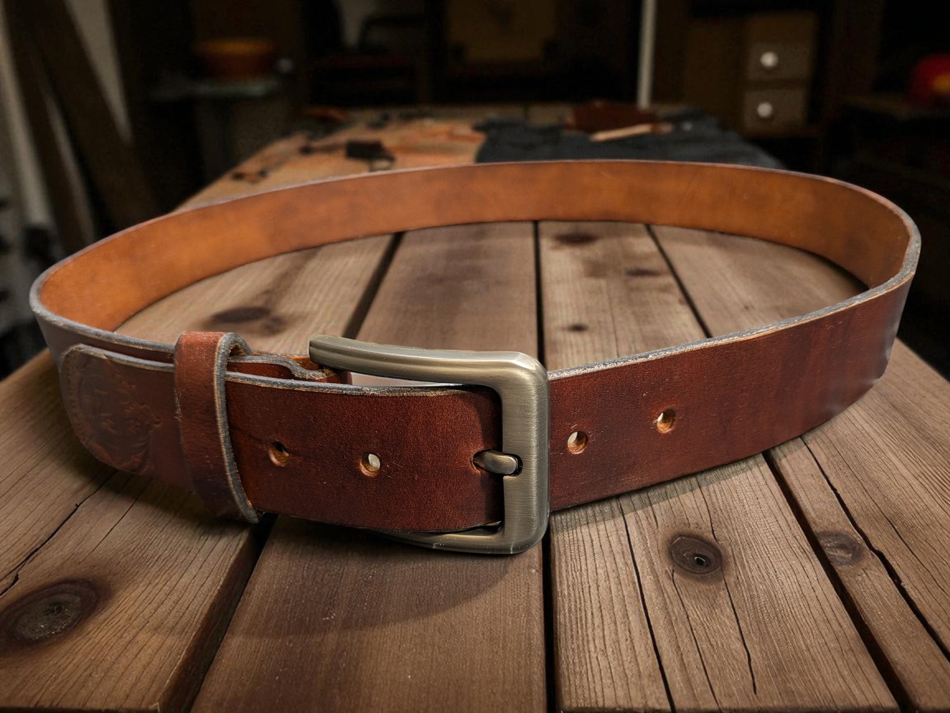 A Brown Leather Belt displayed on a rustic workbench.