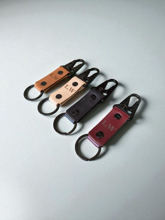 Set of leather keychains with initials on a light gray background