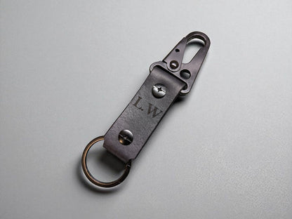 Black leather keychain with metal clip on a gray background