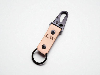 Leather keychain with metal clip and initials 'L.W.' on a light gray background