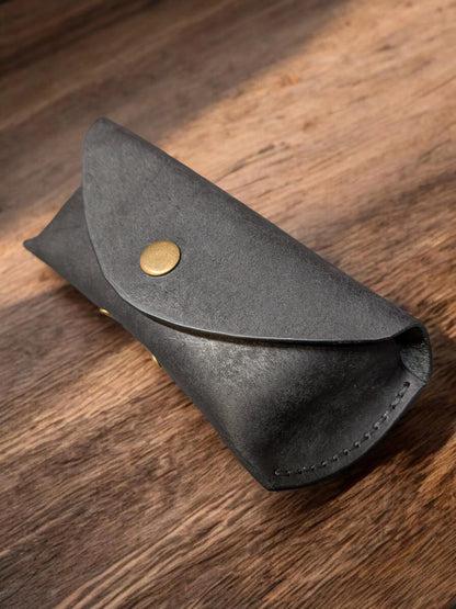 Handmade black leather sunglasses case in Badalassi Pueblo with brass snap closure, angled view