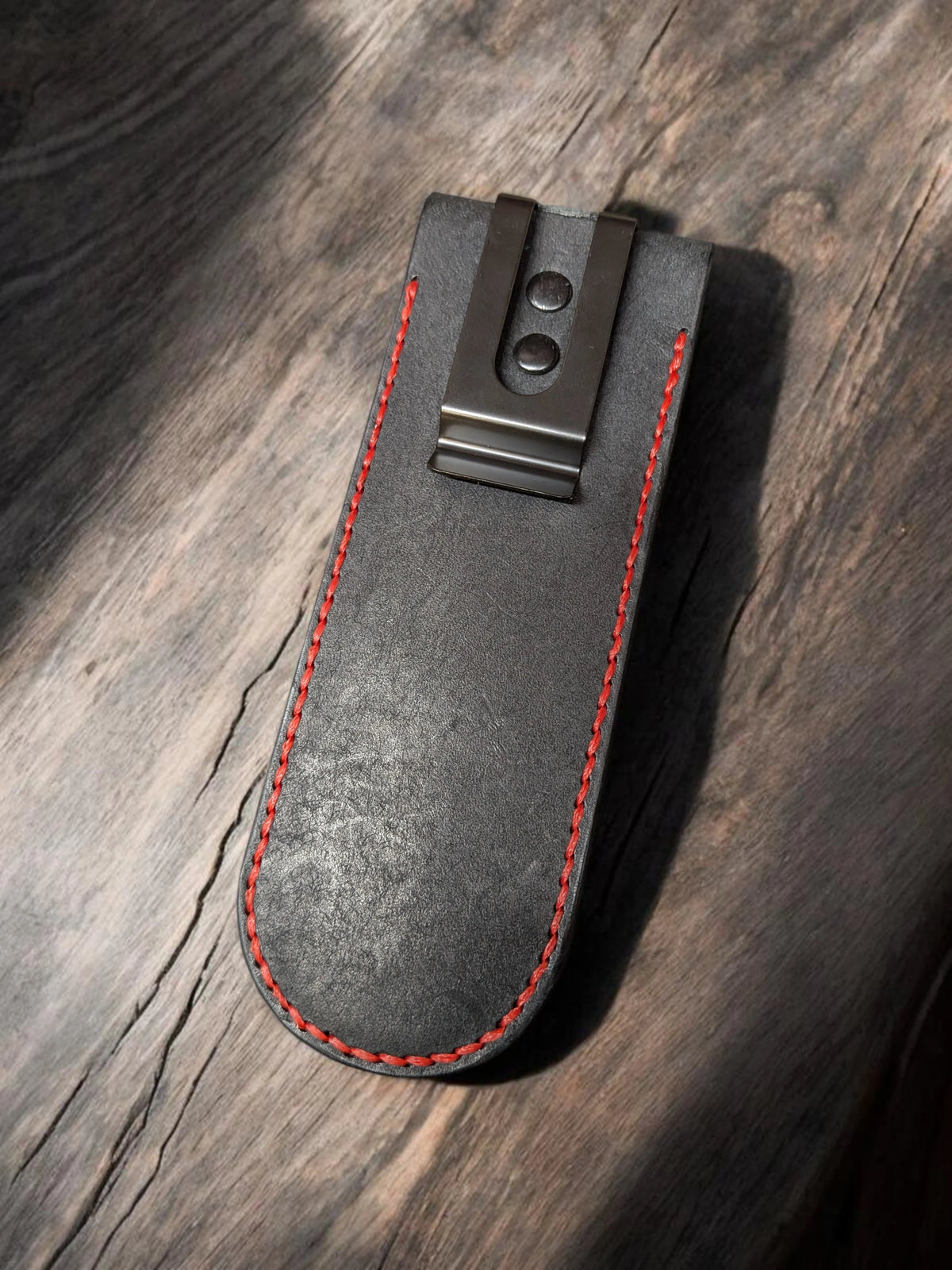 Back of the black leather pen holder showing the metal belt clip and red stitching