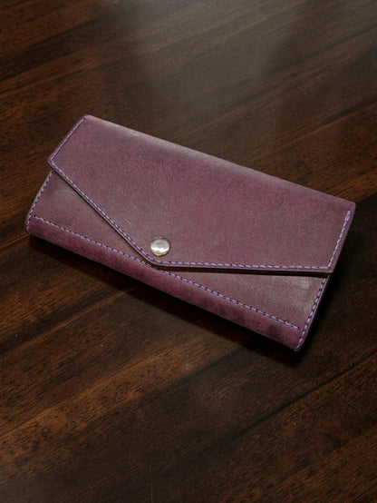 Ladies long wallet in purple Badalassi Pueblo leather with envelope flap, snap closure and lilac stitching, on a wooden table