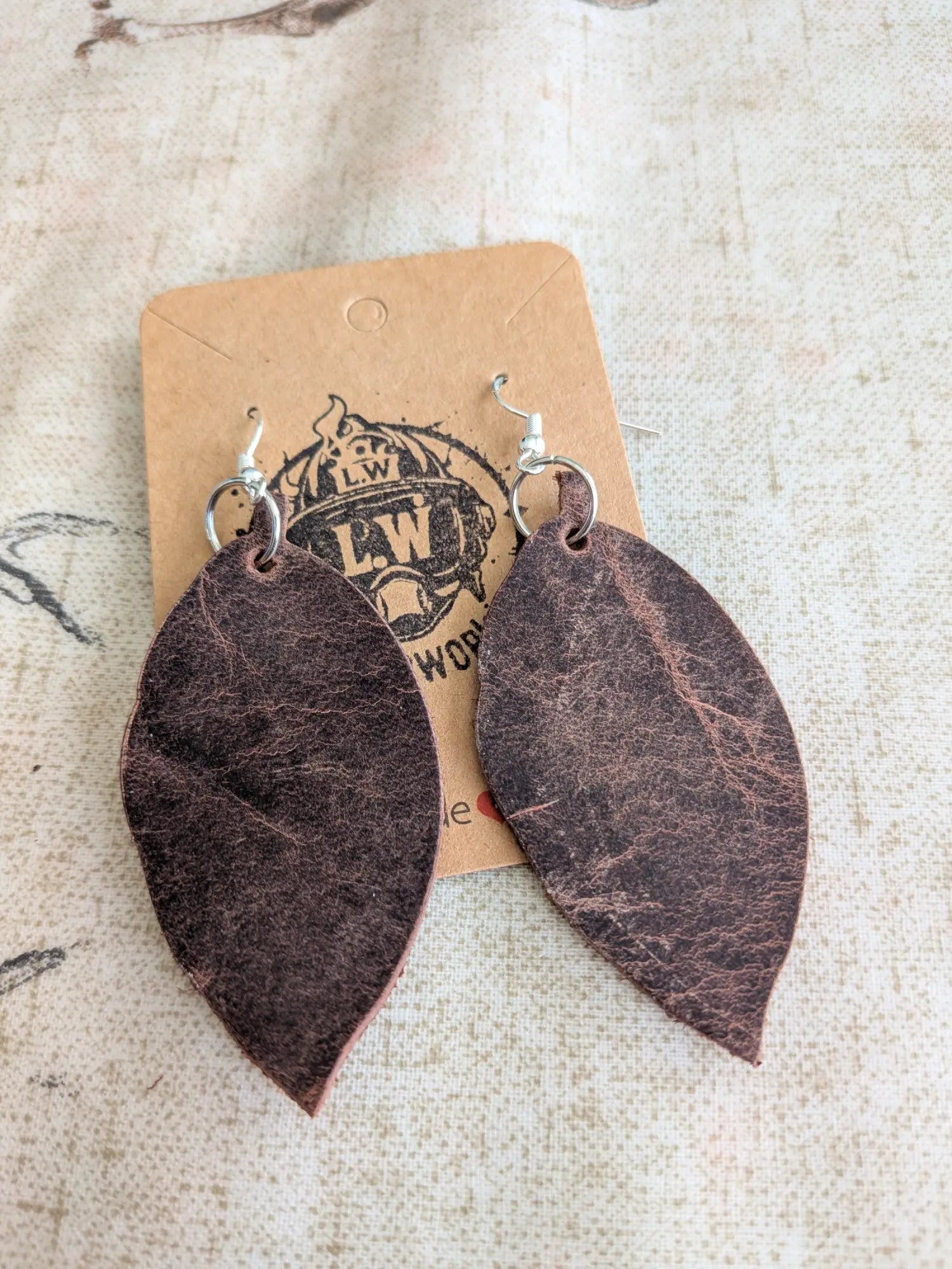 Dark brown leaf-shaped leather earrings with silver hooks made from brown leaf pullup leather