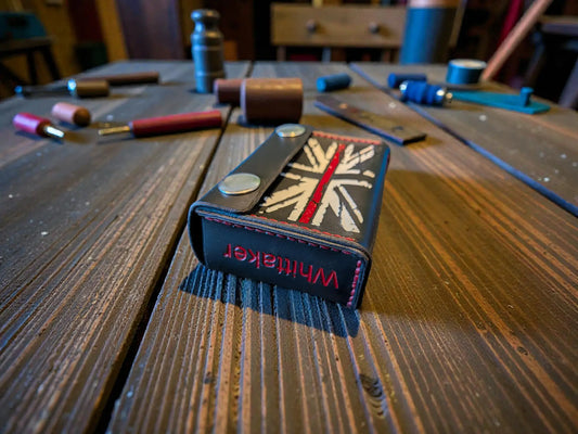 Custom Fire Service Alerter Case (Birdy & Multitone Type) on a wooden surface with leather crafting tools in the background, showcasing detailed stitching and design.