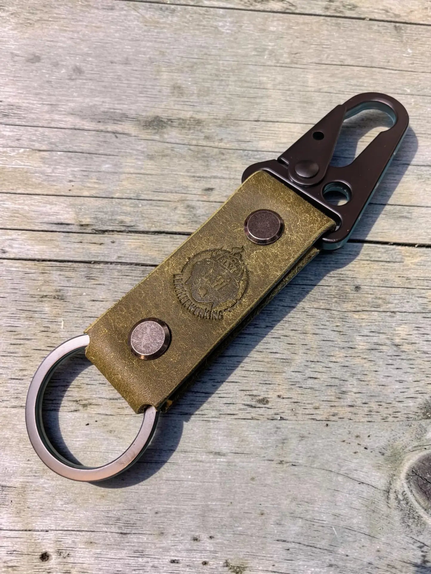 Vintage-style olive green custom tactical leather keychain with brass clasp and embossed crest for personalized use