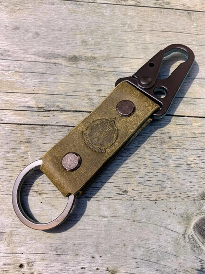 Vintage-style olive green custom tactical leather keychain with brass clasp and embossed crest for personalized use