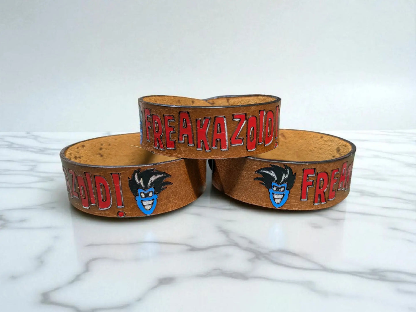 Brown leather freakazoid inspired leather bracelet with red lettering and blue cartoon face design handcrafted full grain