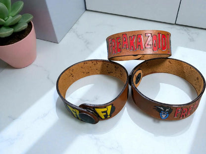 Brown leather wristbands with colorful freakazoid inspired leather branding and cartoon character designs on cuff bracelet