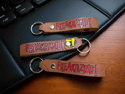 A Freakazoid themed Handmade Leather Keychain displayed on an office desk