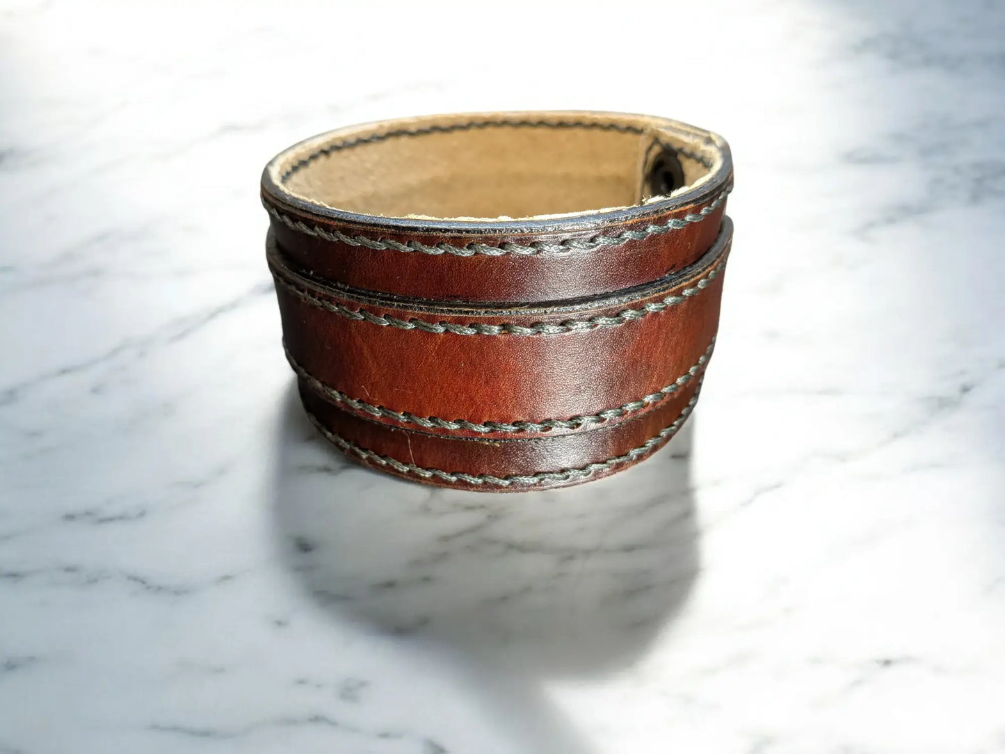 Brown full grain leather cuff bracelet on a marble surface