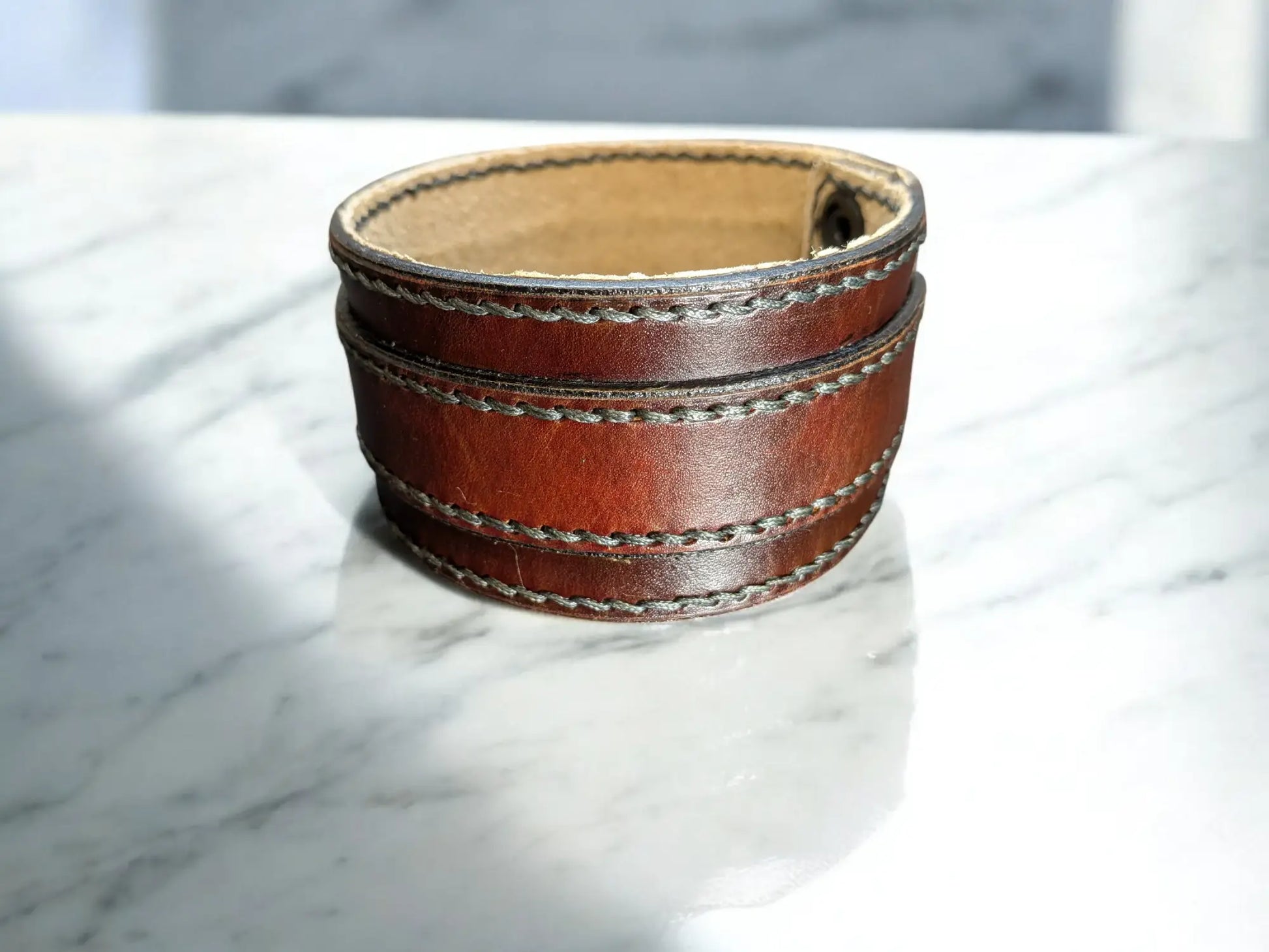 Brown leather cuff bracelet on a marble surface