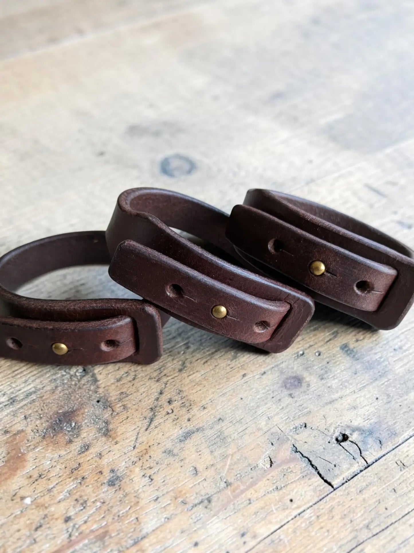 Dark brown full grain leather wrap bracelet with brass rivets and rectangular buckle closures for stylish wear
