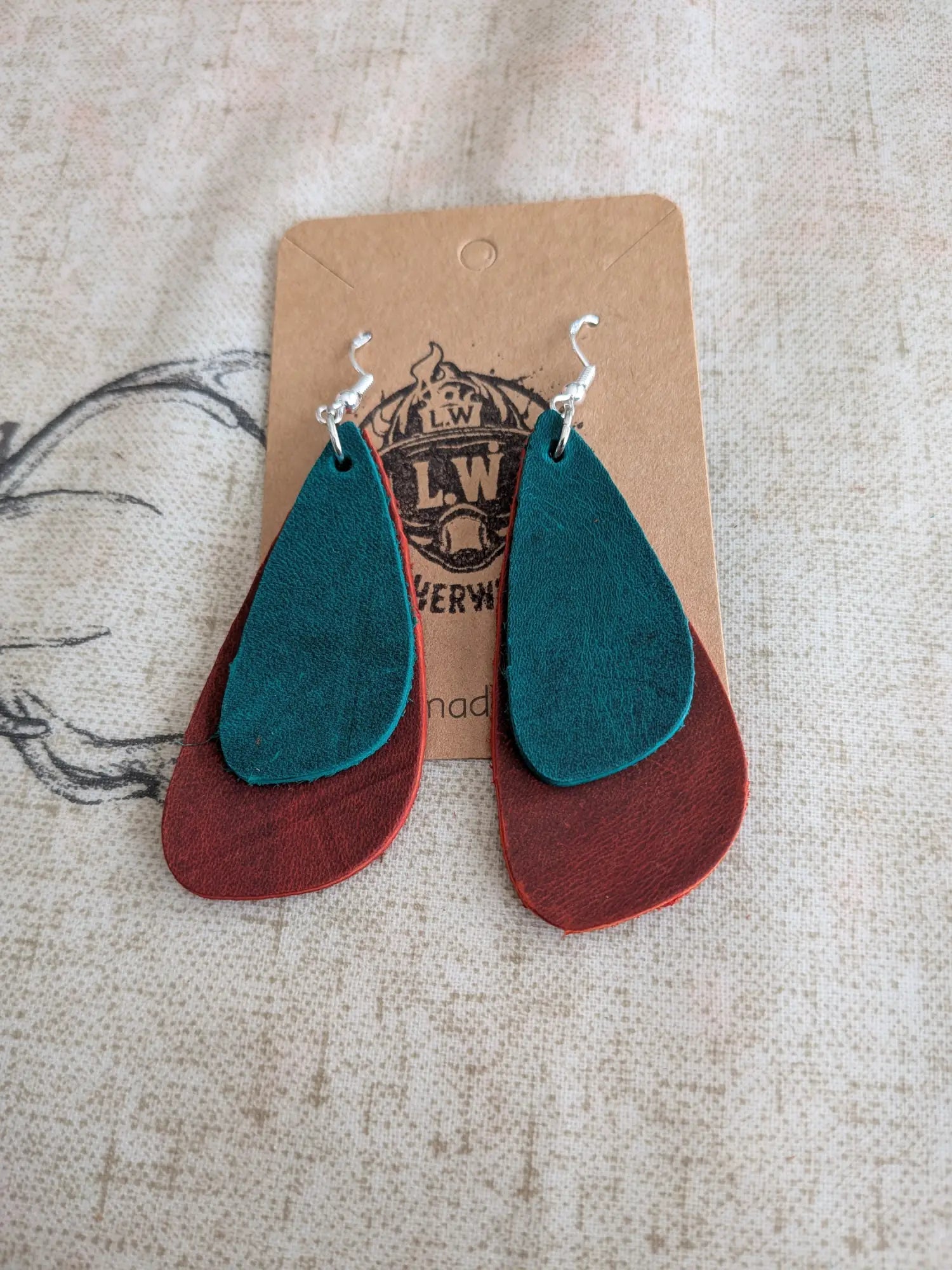 Teal and rust-colored layered leather earrings with silver hooks made from orange oregano leather for stylish wear