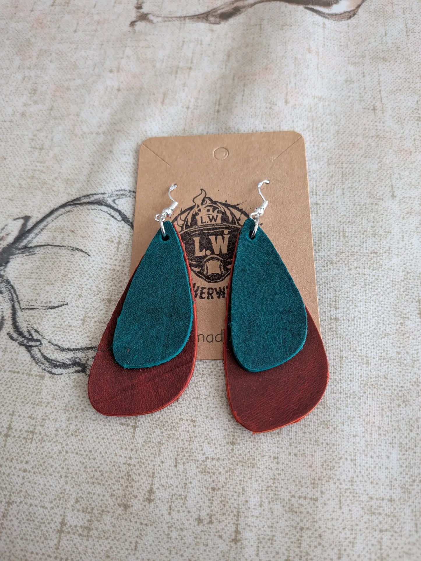 Teal and rust-colored layered orange oregano leather earrings with silver hooks in a drop leather earrings design