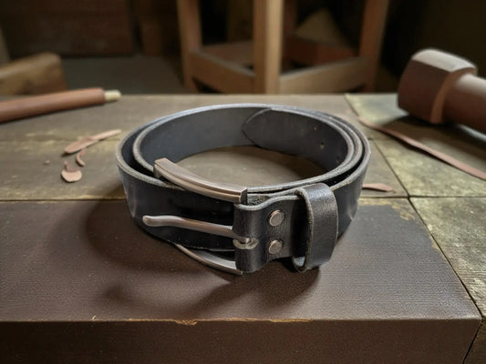 Black leather belt with silver buckle on a wooden surface