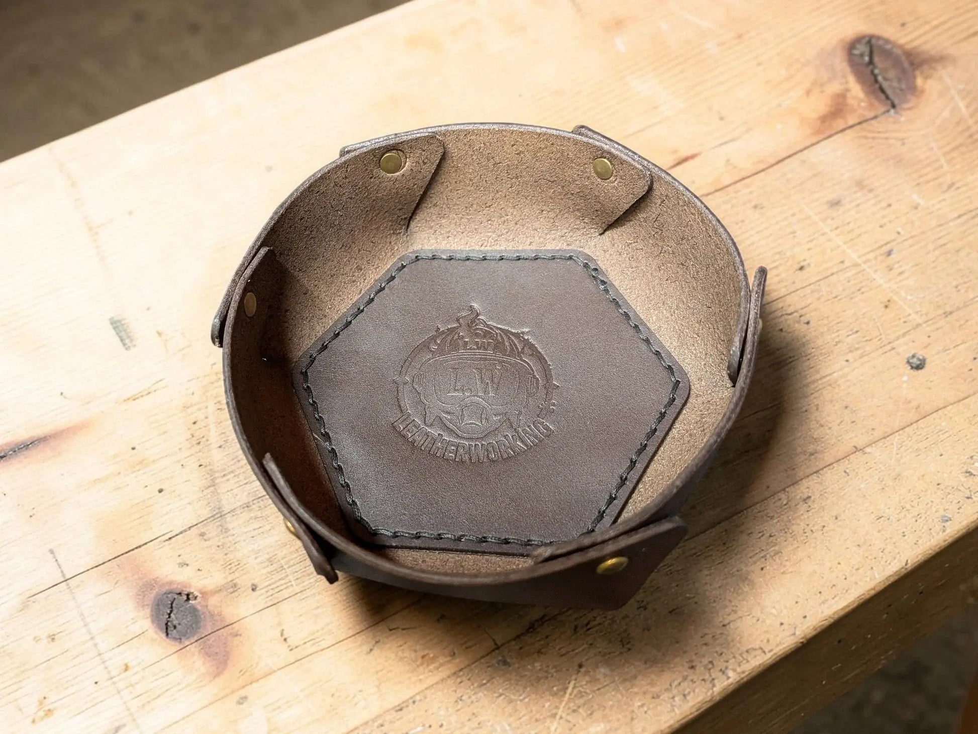 Brown leather hexagonal dish with stitched edges and embossed crest made from vegetable tanned full grain leather