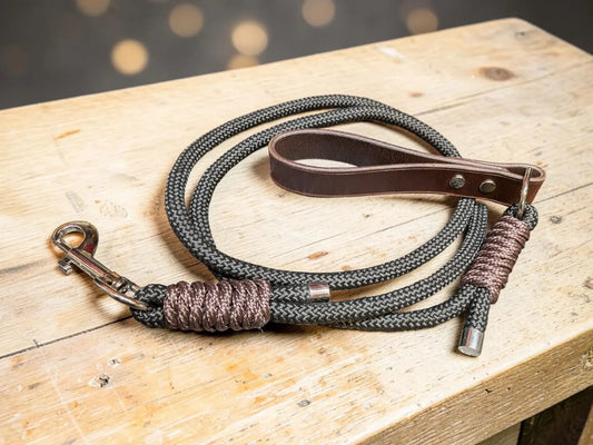 Full grain leather dog lead with dark gray braided rope and brown leather handle featuring metallic hardware