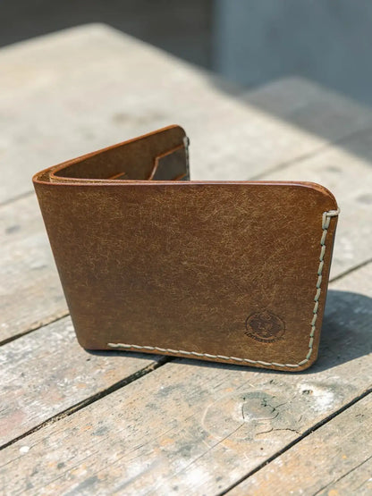 Brown leather bifold wallet with light stitching and embossed logo corner mealstrom badalassi pueblo design