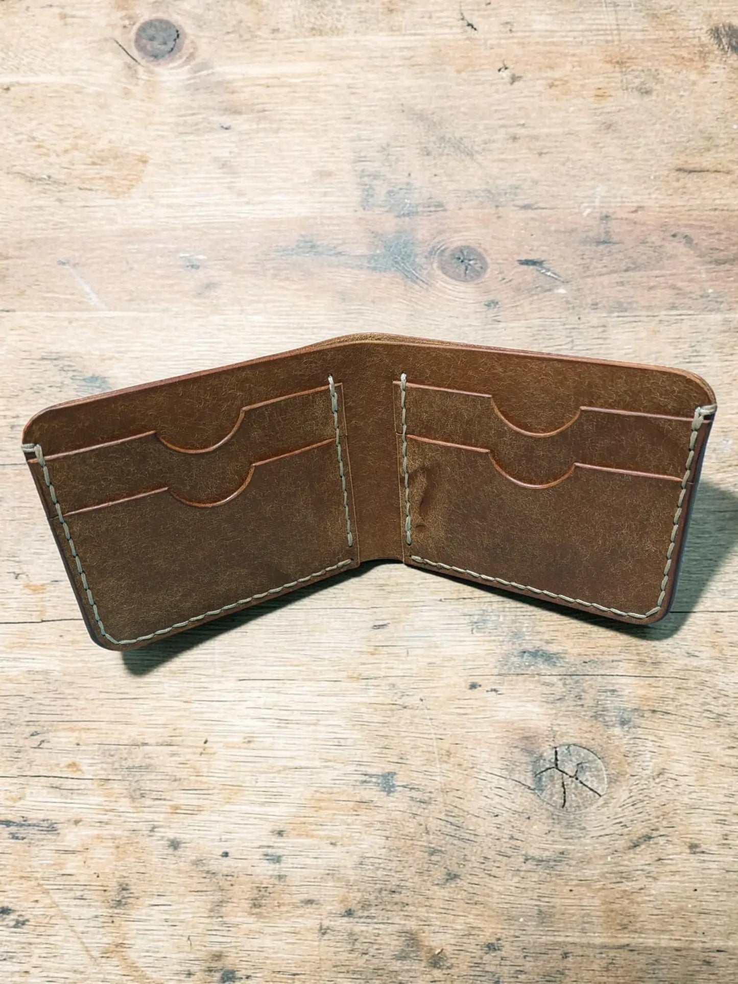 Brown leather bifold wallet with visible stitching and multiple card slots mealstrom badalassi pueblo