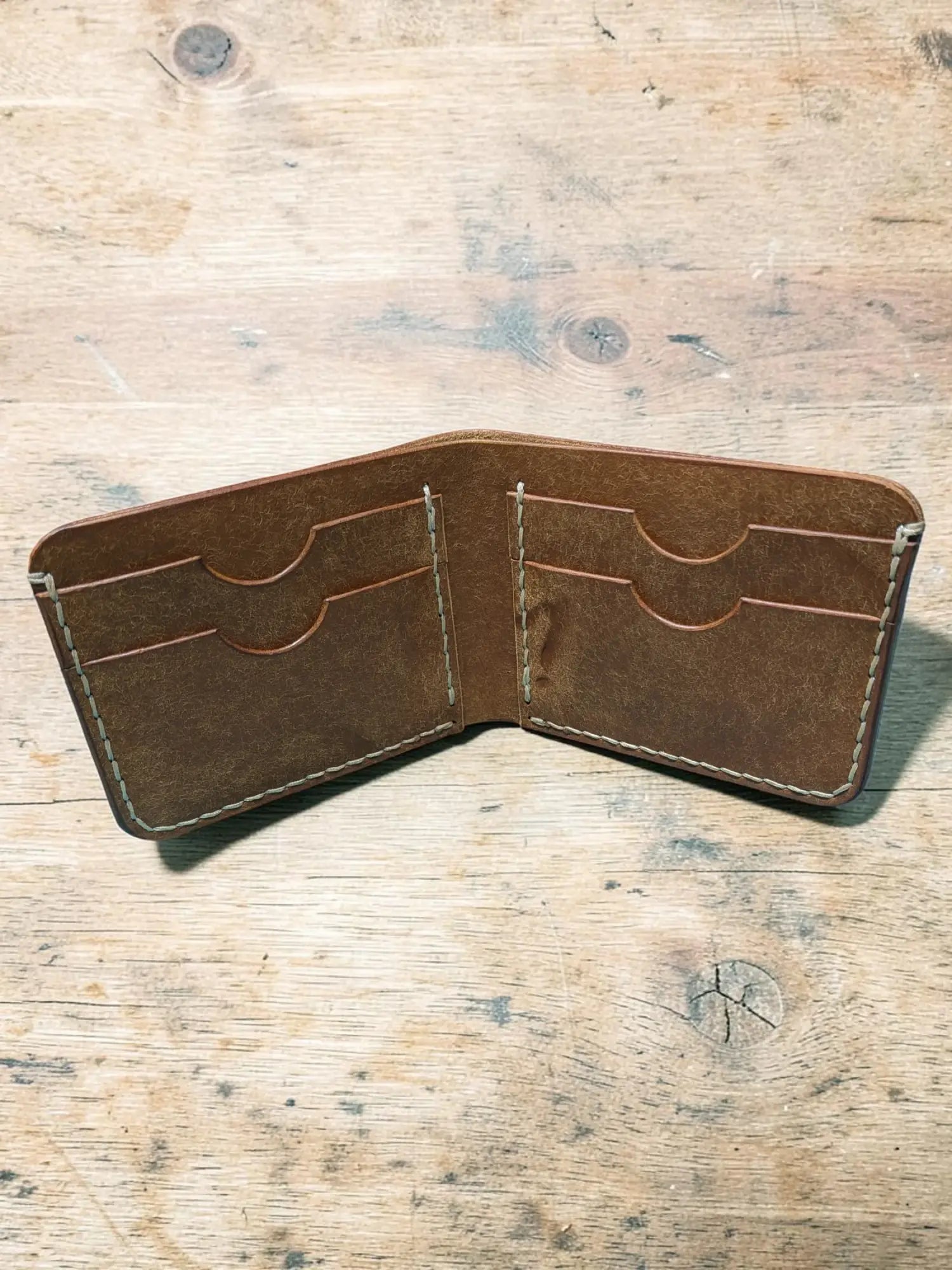 Brown leather bifold wallet with visible stitching and multiple card slots mealstrom badalassi pueblo