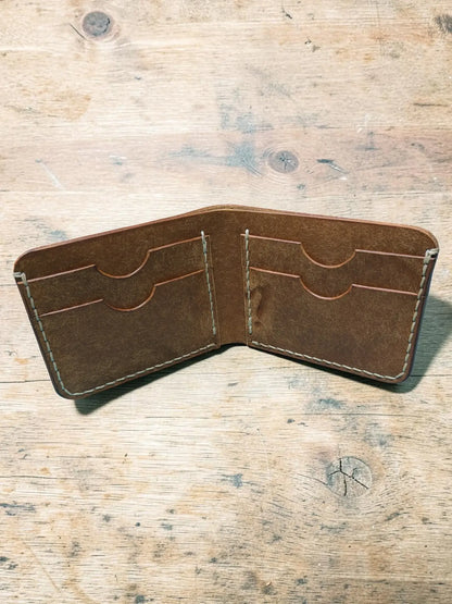 Brown leather bifold wallet with visible stitching and multiple card slots mealstrom badalassi pueblo