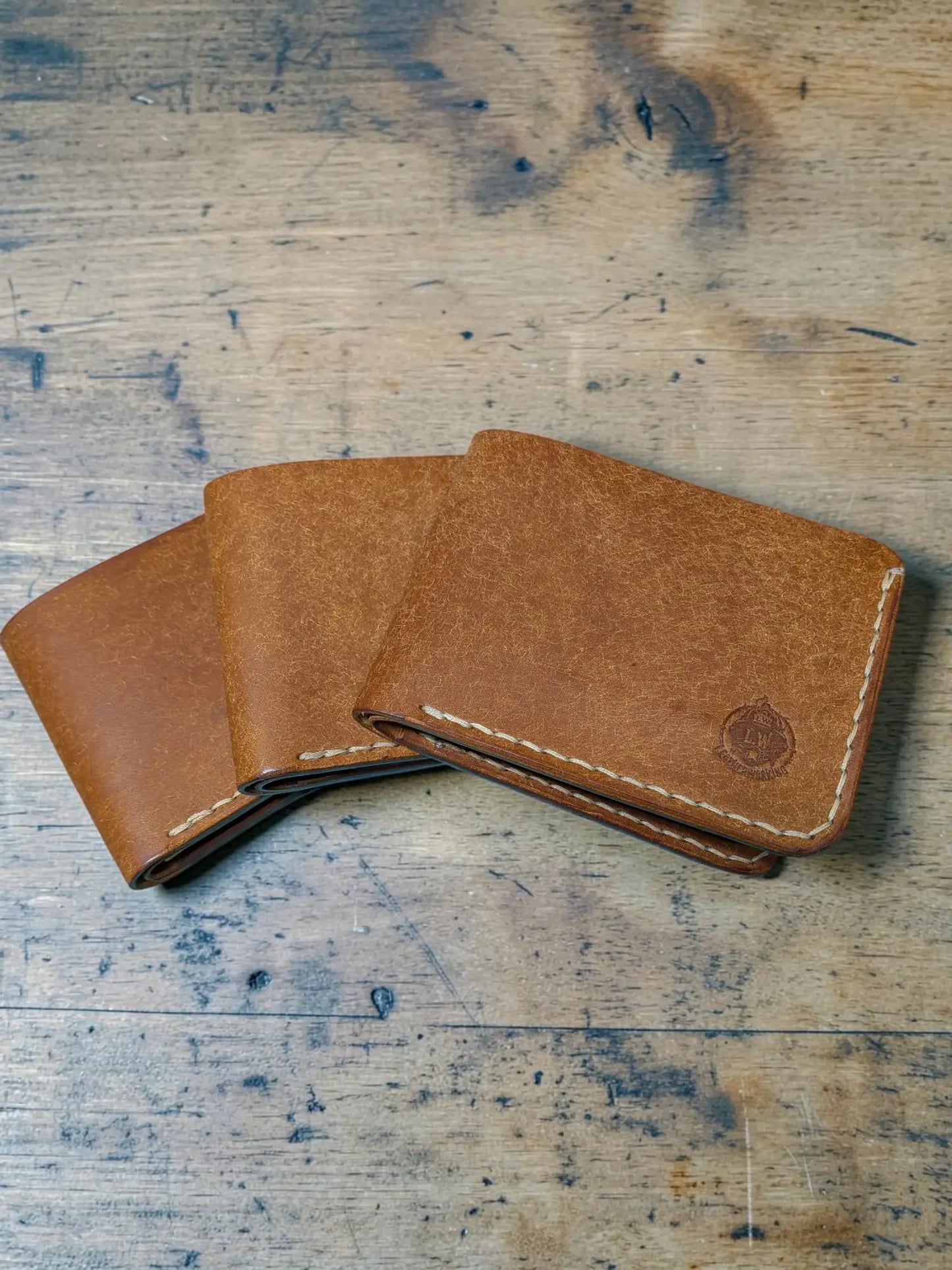 Tan leather bifold wallet with white stitching and embossed logo corner mealstrom badalassi pueblo design