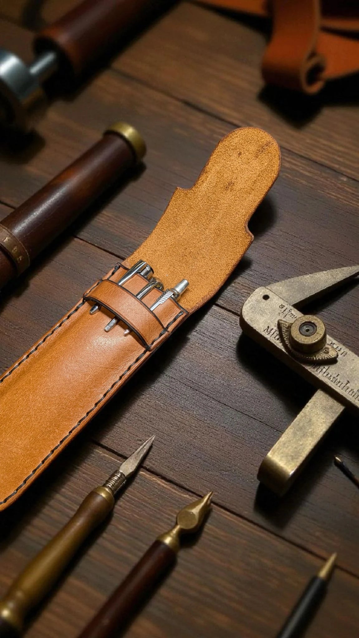 Set of tools including a leather sheath on a wooden surface