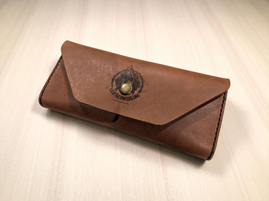 Brown leather Sunglasses Case with a logo on a light beige background