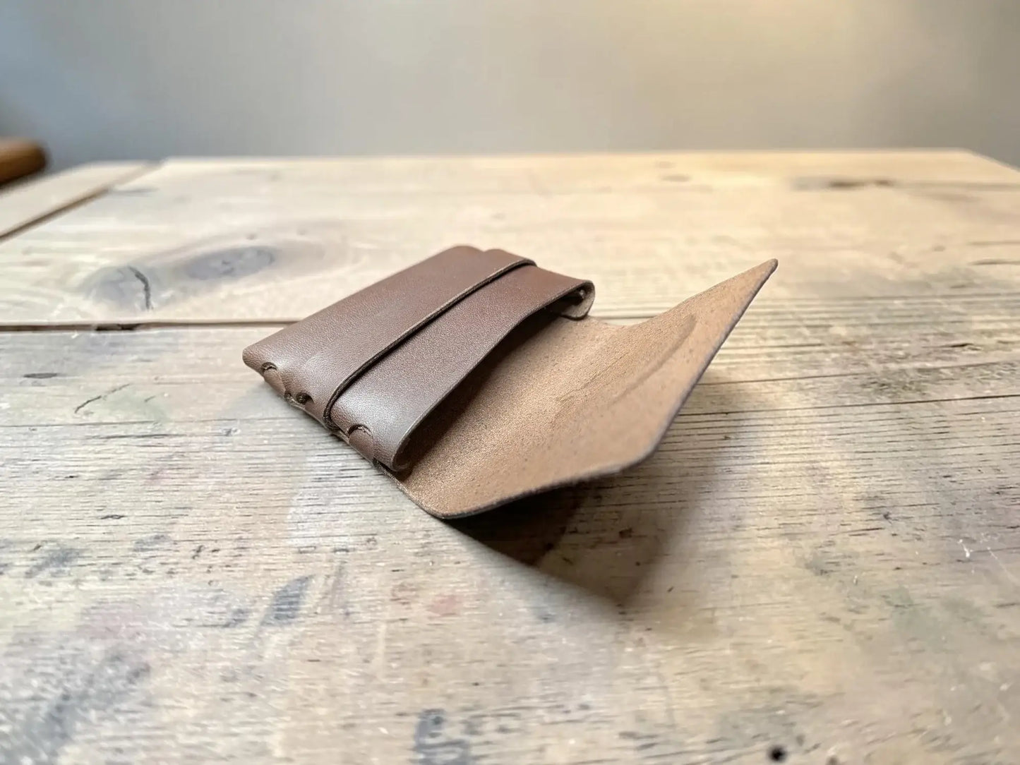 Brown leather card holder with visible stitching minimalist design made from full grain leather for everyday use