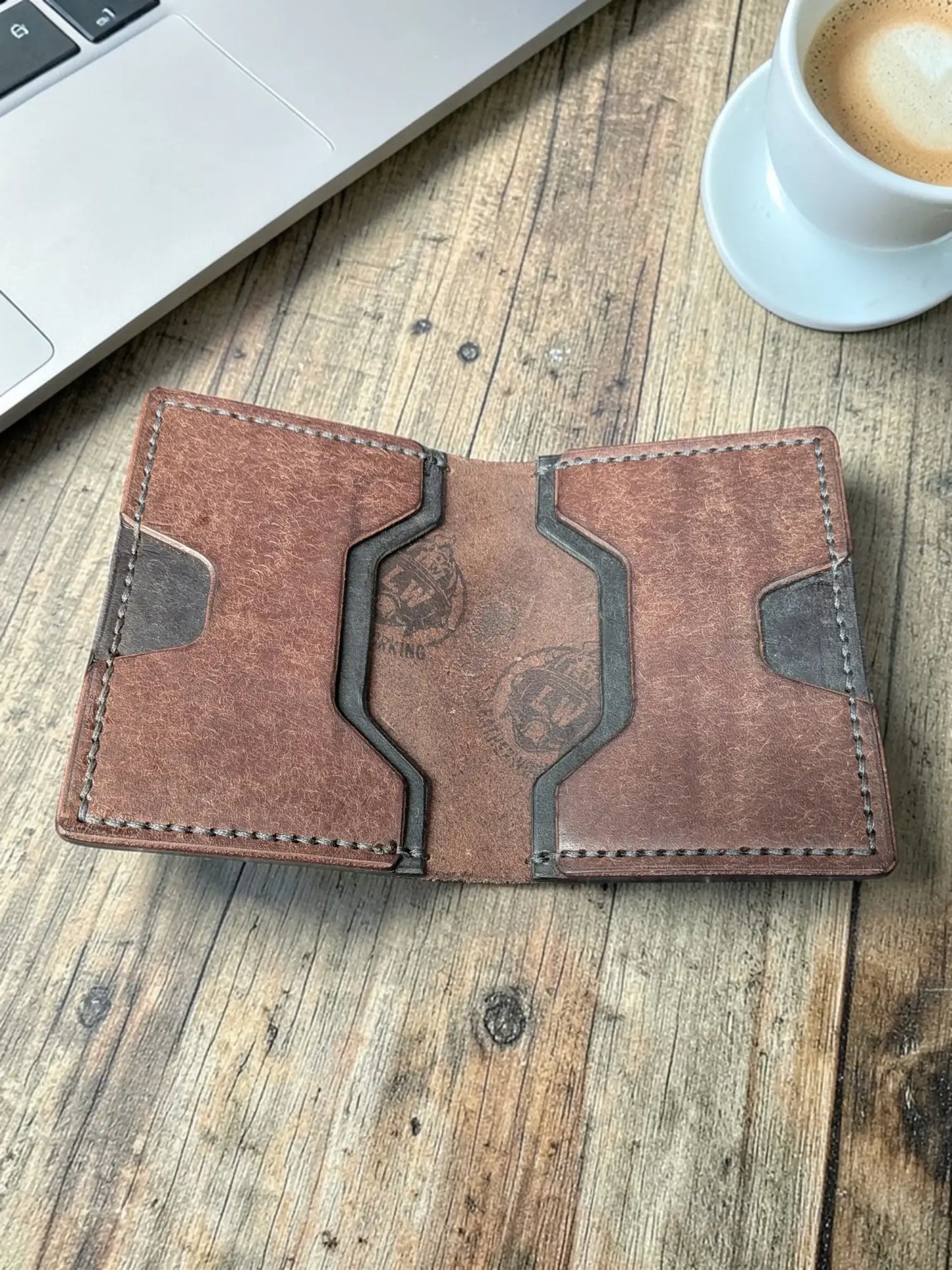Opened brown leather Venturi wallet showing card slots and embossed logo, flat lay on a wooden desk
